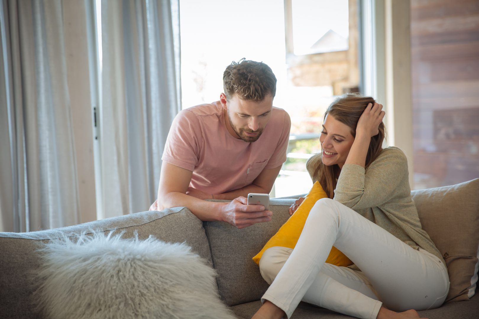 Man and woman using their smart phone to control their motorised blinds