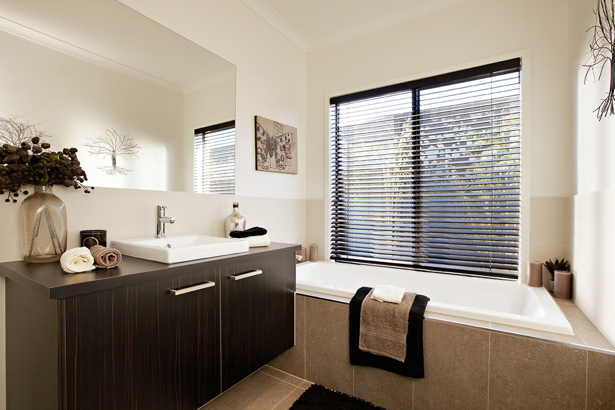 Custom made black bathroom blinds opening next to a white bath black wooden drawer with big mirror