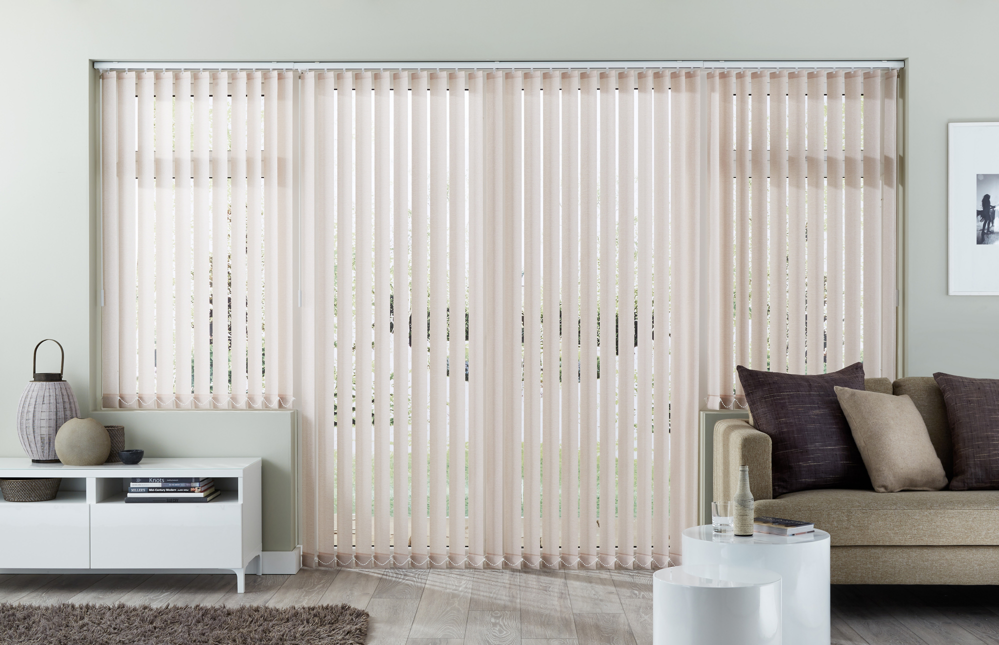 Neutral living room with beige couch and white walls complimented by cream vertical blinds