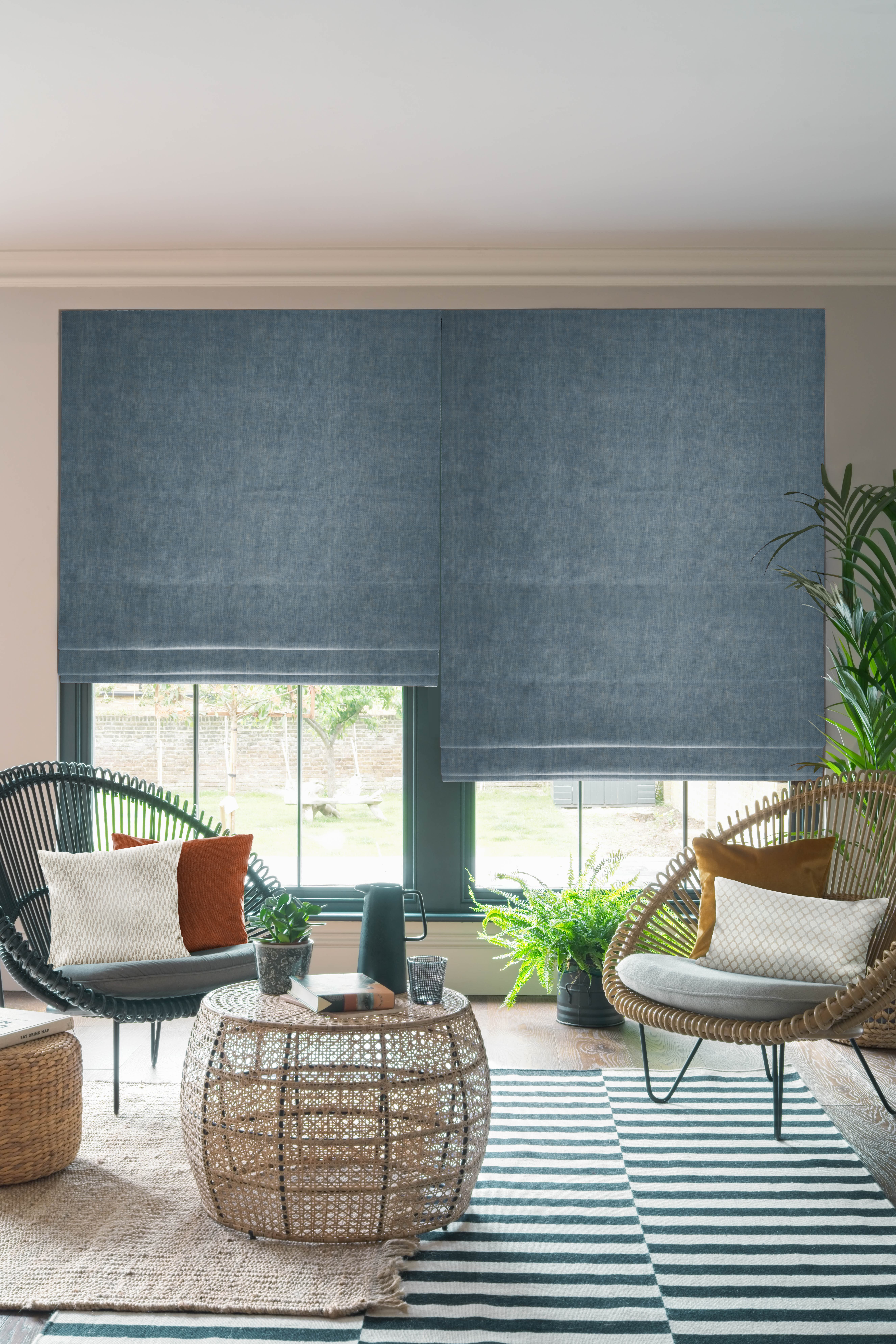 Natural living room with blue roman blinds, wooden chairs, and striped carpet