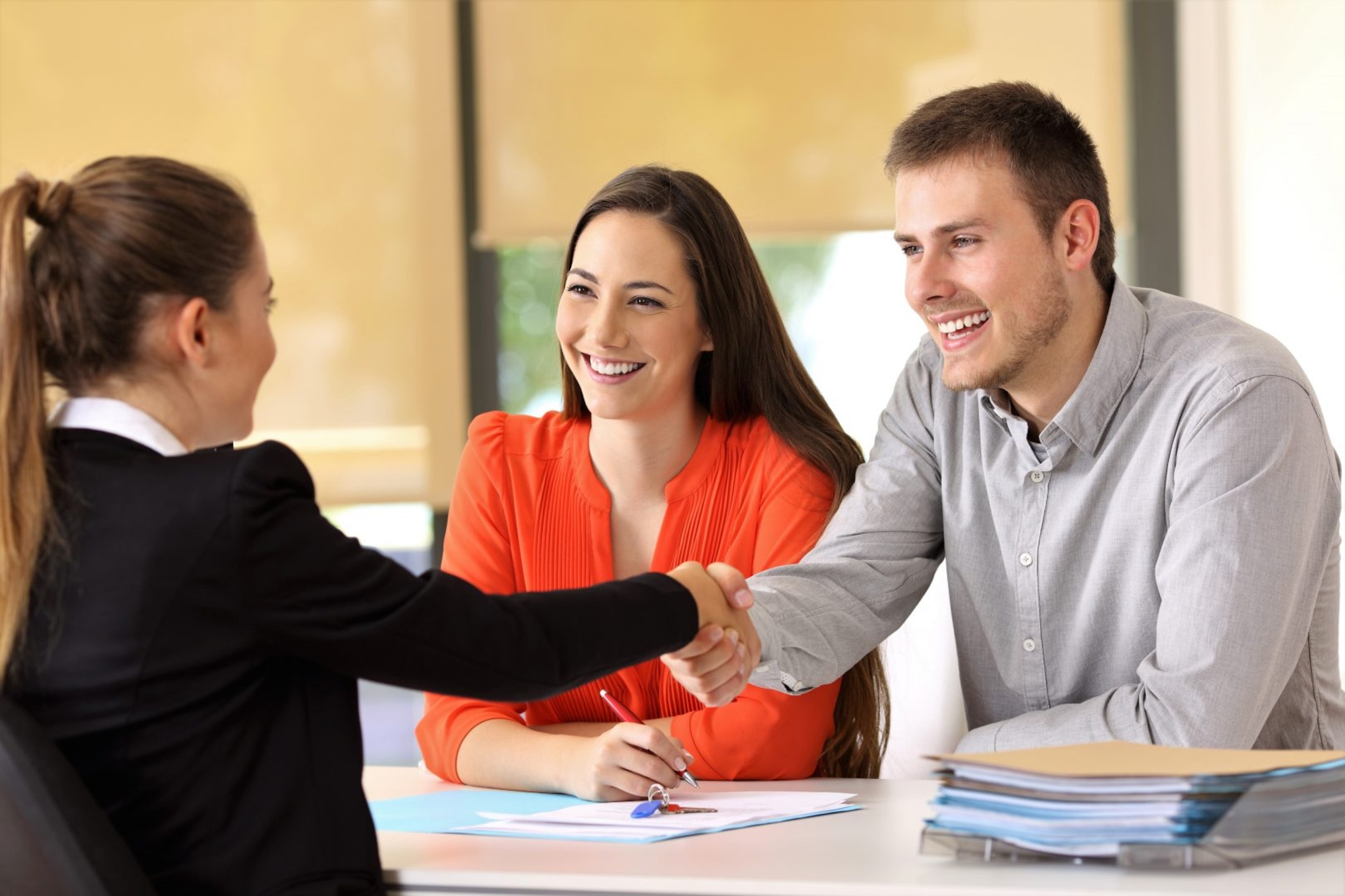 A salesperson having a consultation with a man and woman smiling and shaking hands