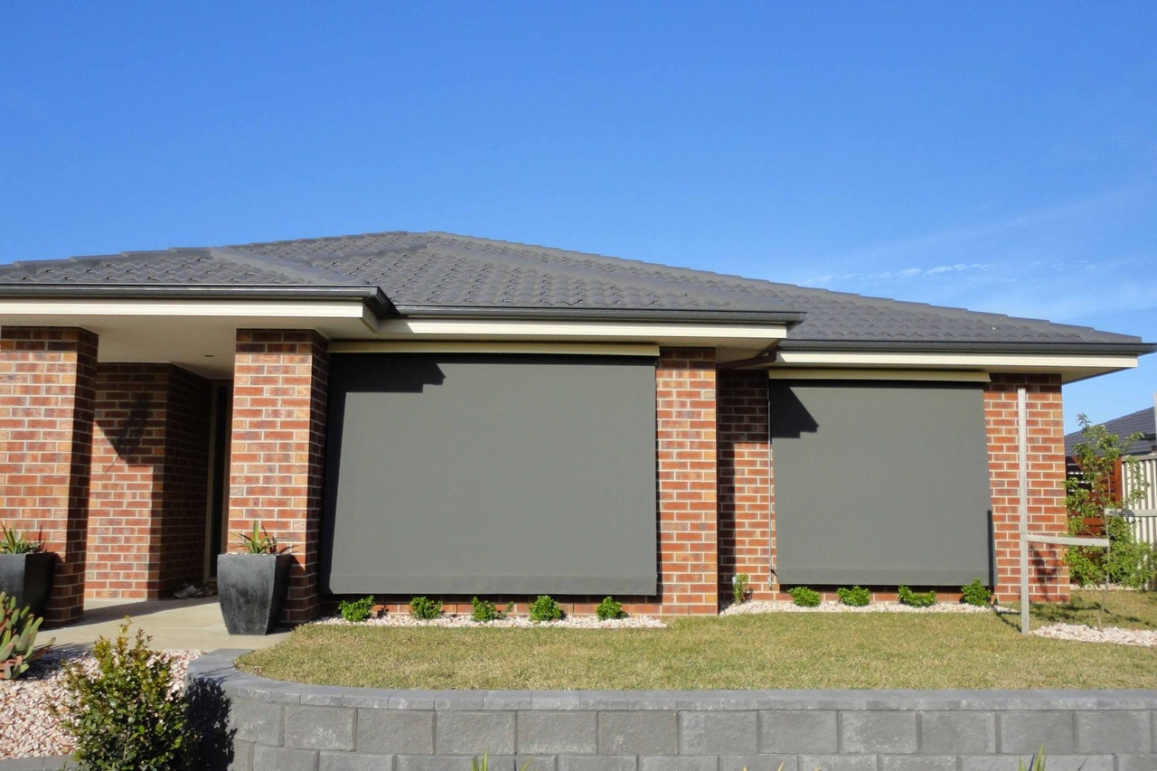 Brick one storey house with dark grey awnings on the front windows