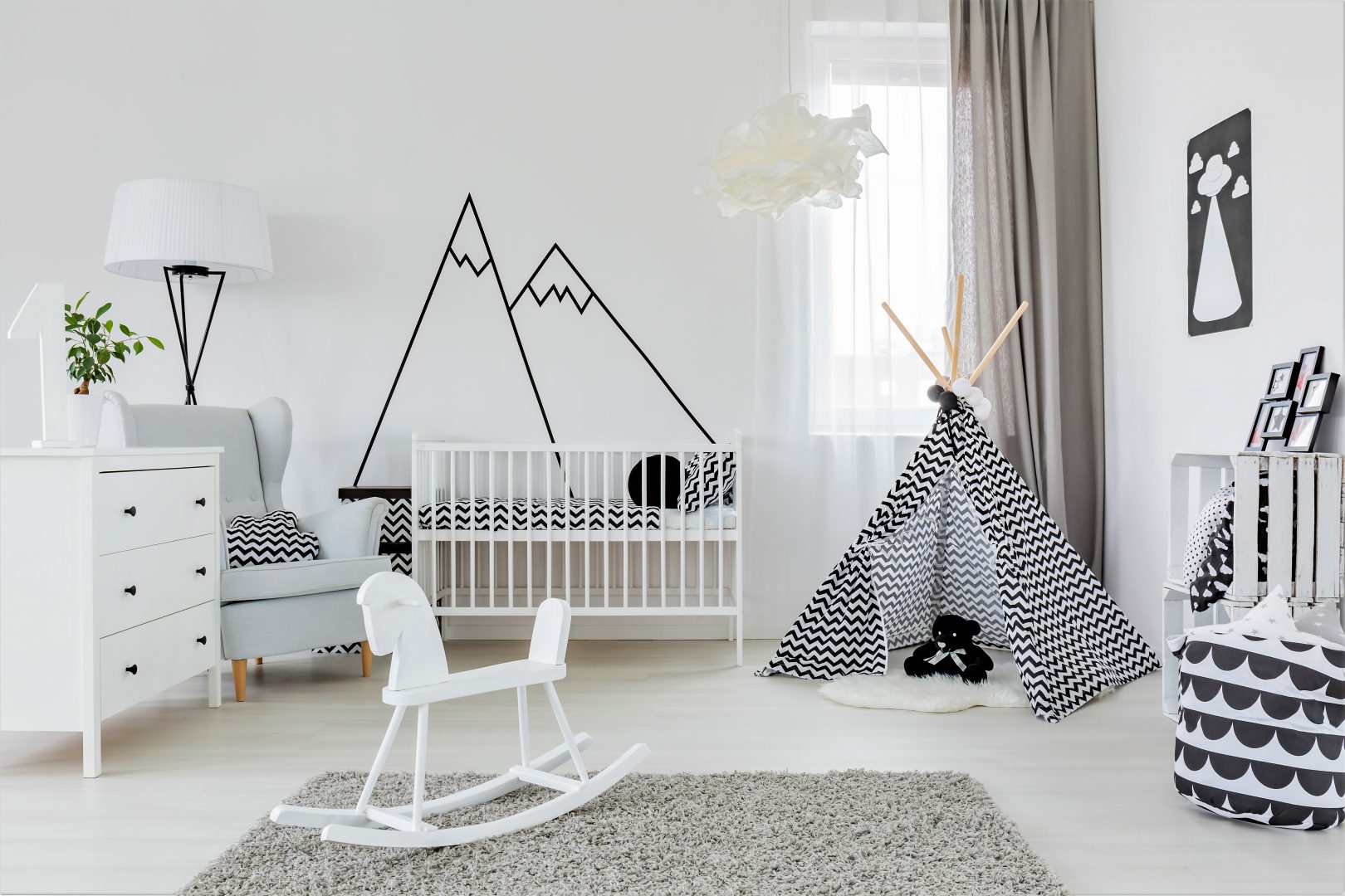 Child's room with white cot and black and white decor with white sheer curtain paired with beige pencil pleat blockout curtain