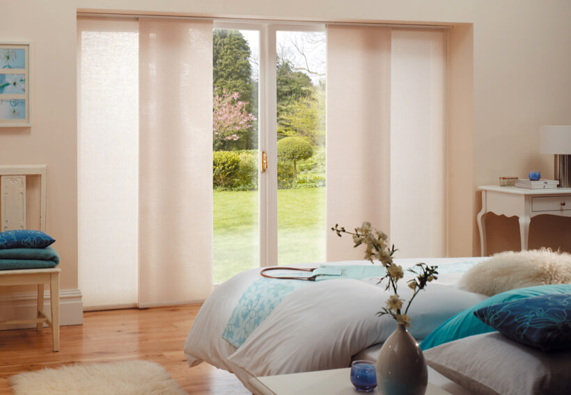 Cream panel blinds over sliding doors in a modern bedroom with timber flooring