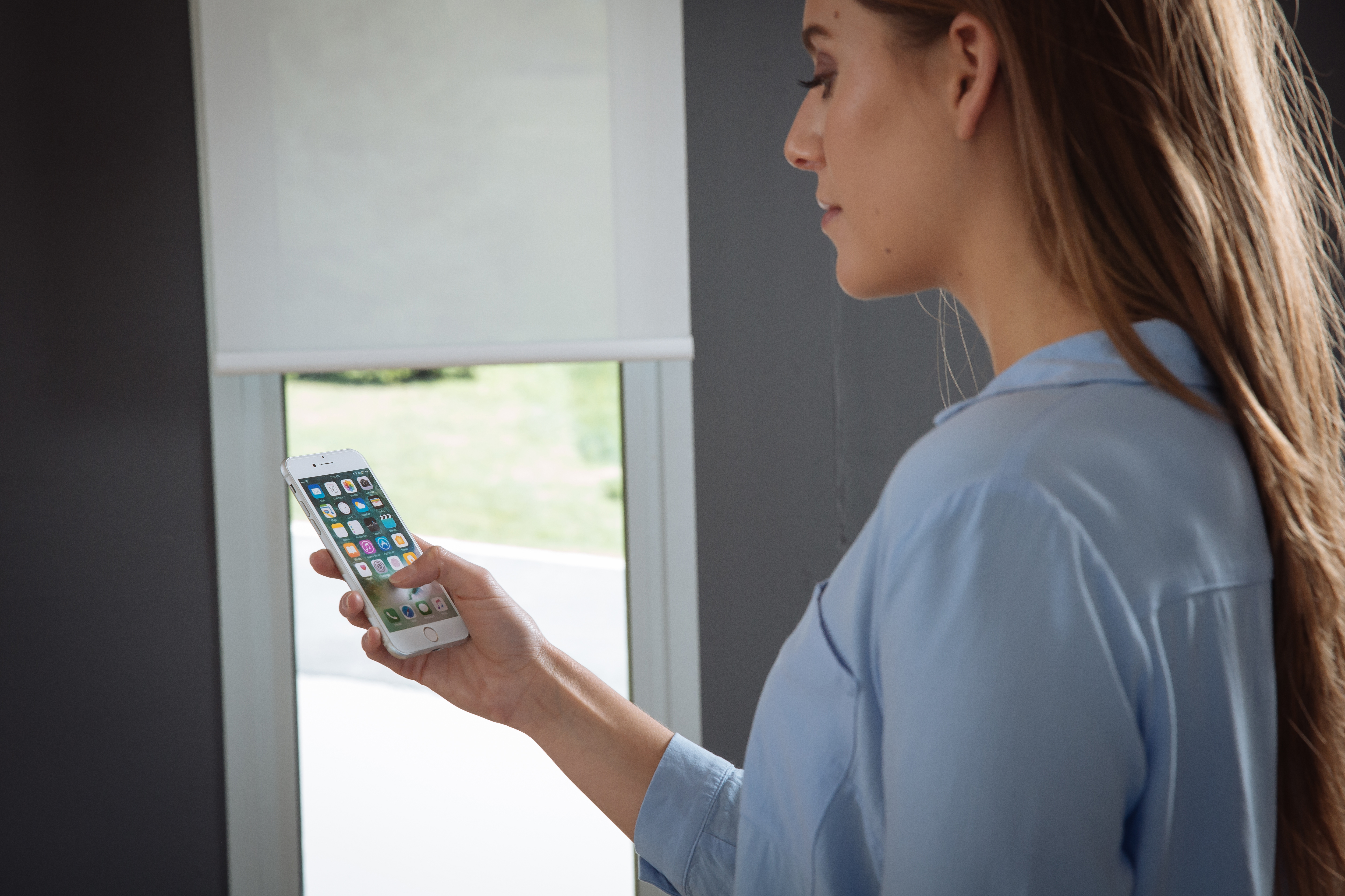 Woman operating her motorised blinds with her smart phone